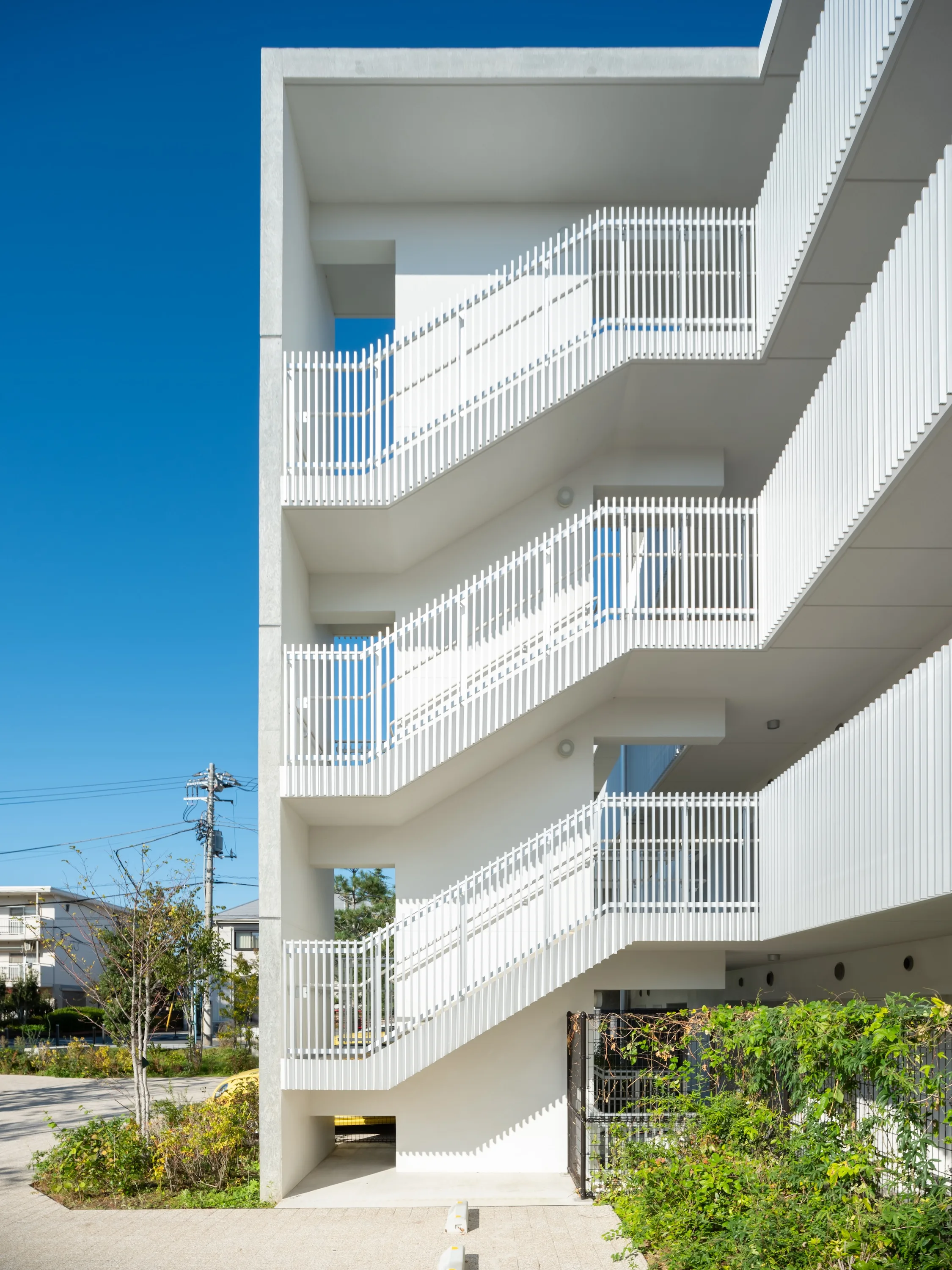 白い外階段と縦格子の手すりが連なる建物外観