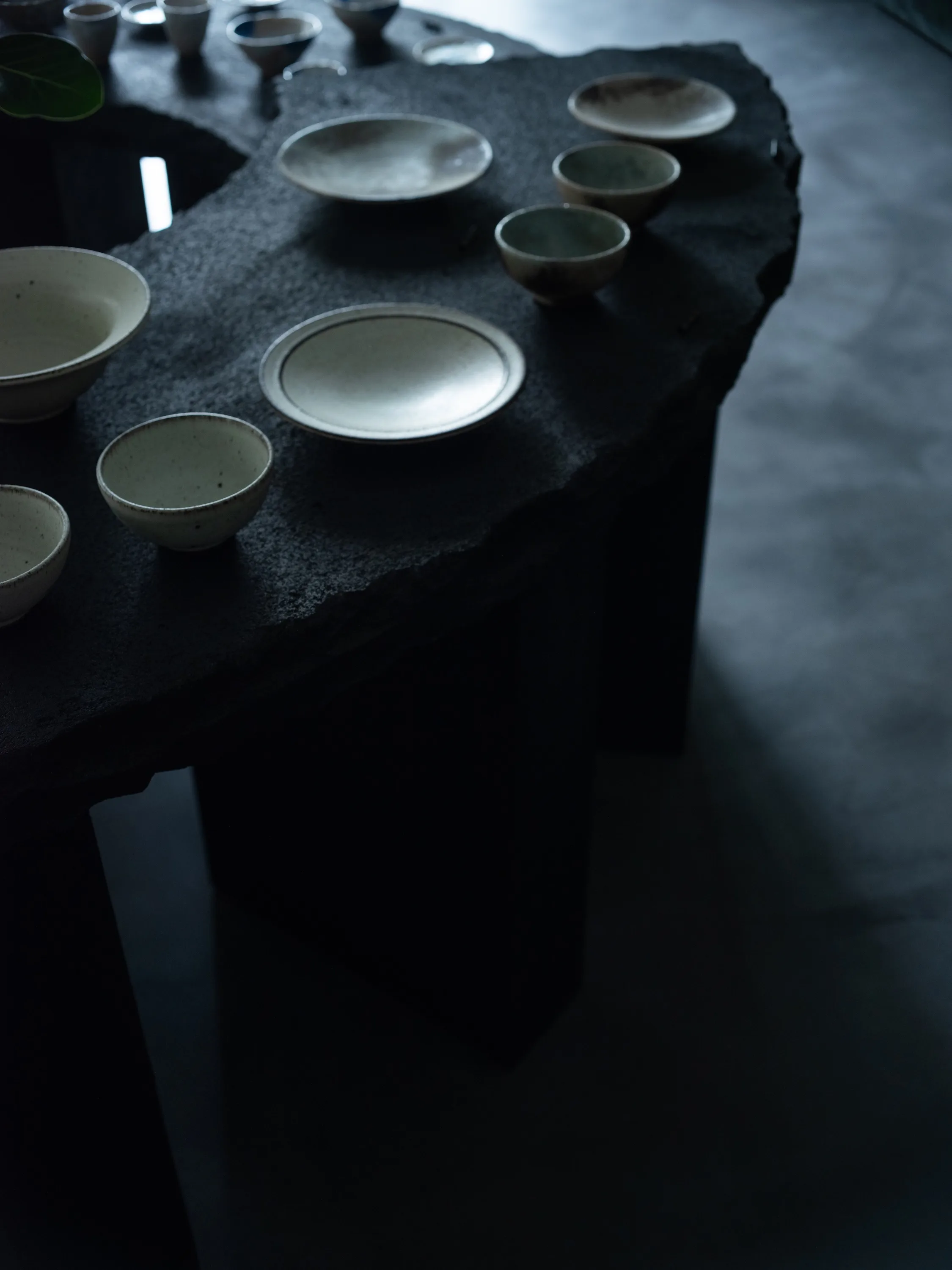 黒い石のテーブルに並ぶ器と皿のディテール